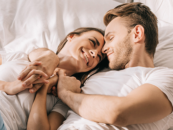 Happy couple laying in bed - hormone therapy south jordan