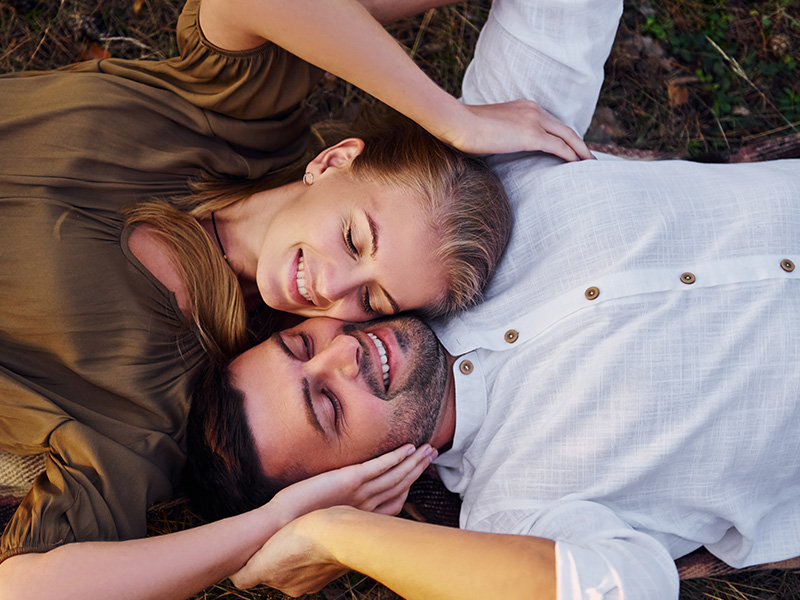 Happy couple laying on the grass - body contouring near me